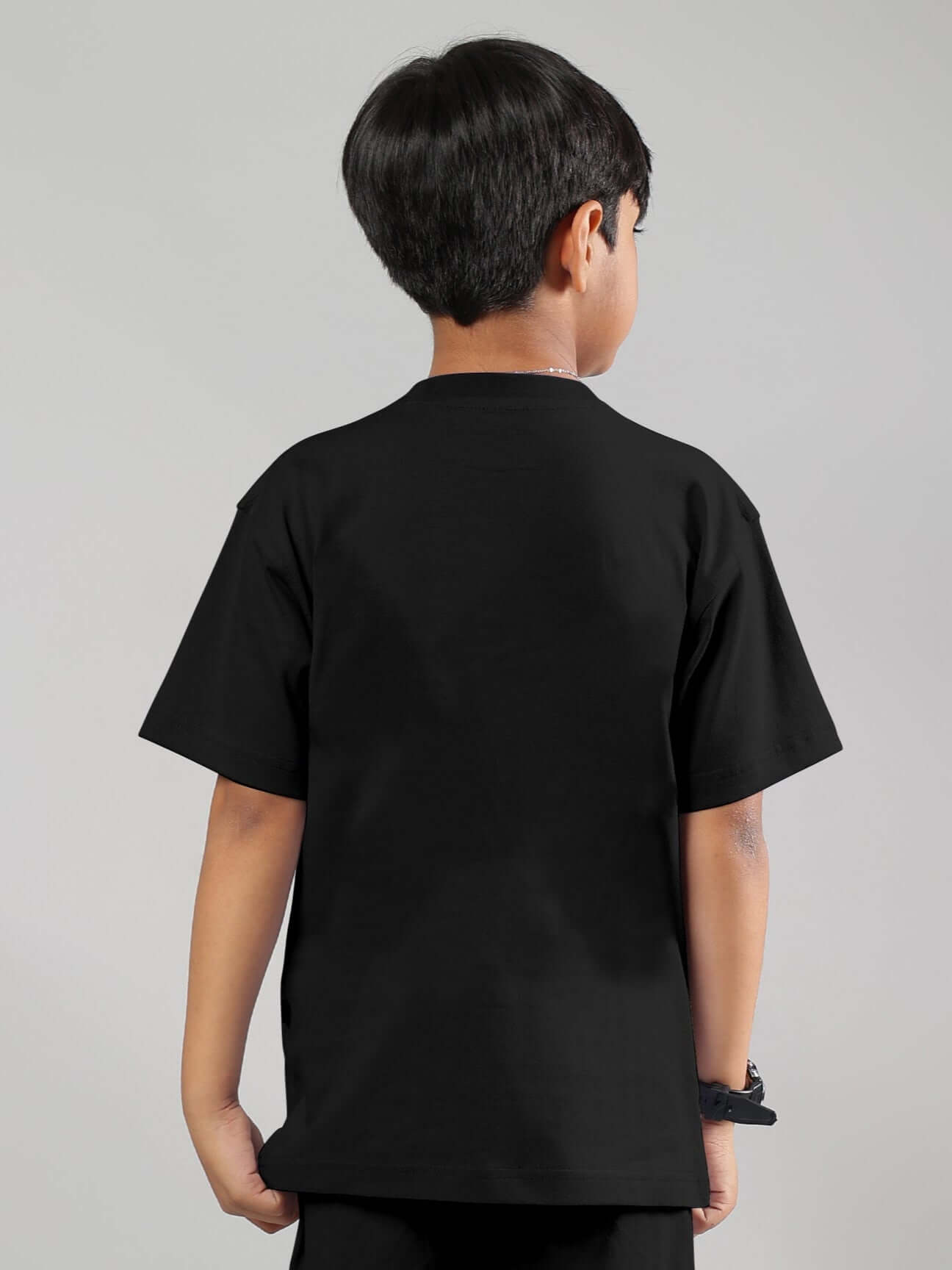 Child wearing FANCY DREAM T-SHIRT FOR BOYS GIRLS BLACK, showcasing the back view of the unisex design in a modern, simple style.