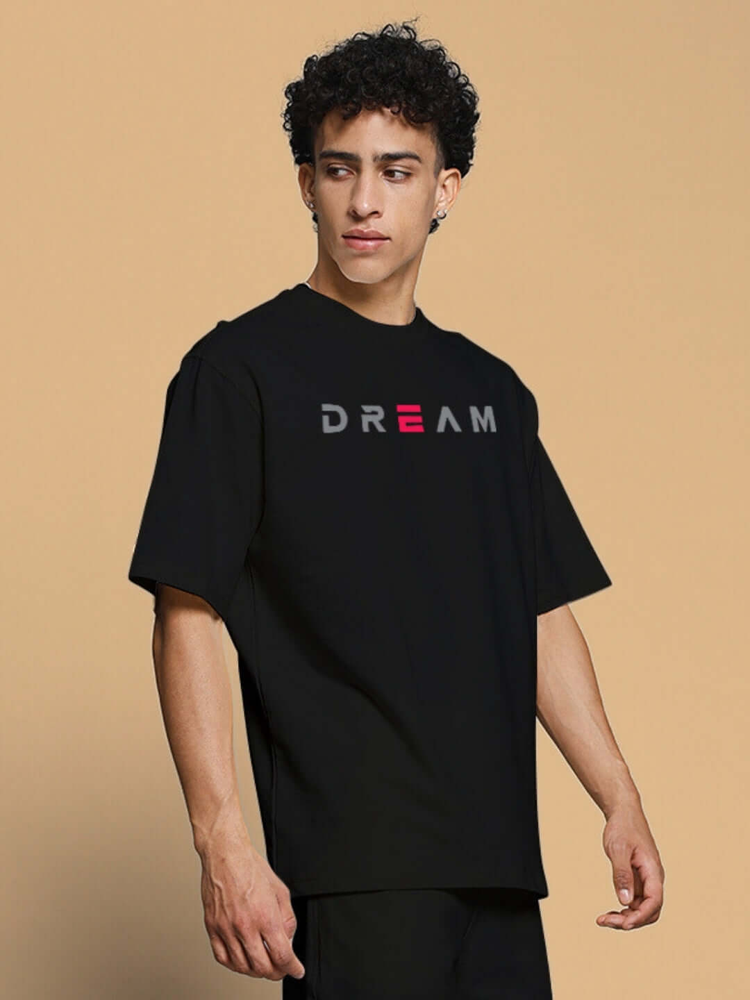 Man wearing FANCY DREAM OVER-SIZED T-SHIRT BLACK with bold 'DREAM' logo, showcasing streetwear style and relaxed fit.