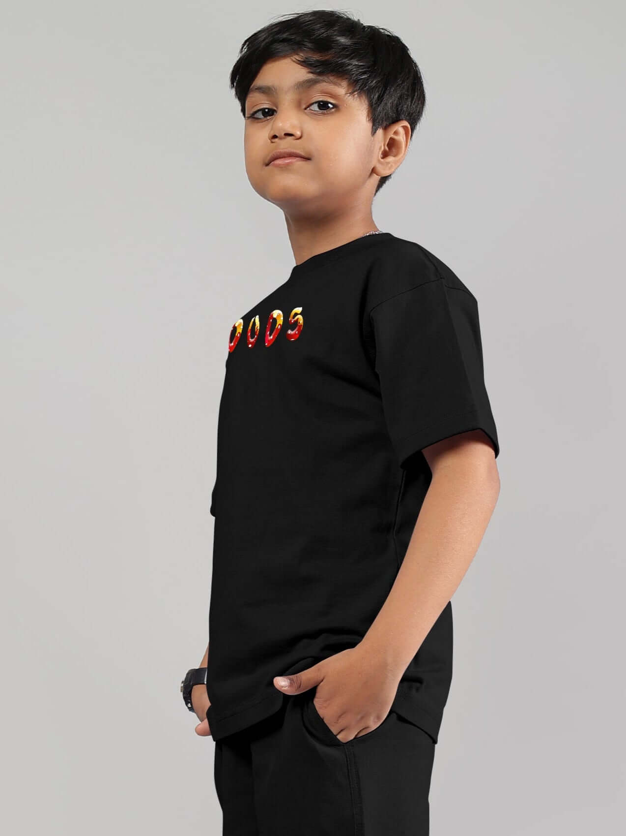 Young boy wearing a black fantasy mushroom T-shirt, hands in pockets, showcasing side view of custom-fit design by DUDS.
