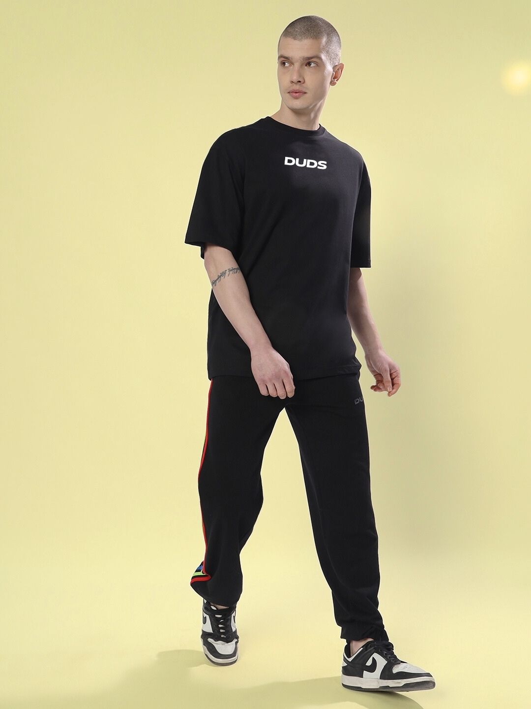 Model wearing FARARI PRINTED OVERSIZED T-SHIRT BLACK in a casual look with black pants and sneakers.