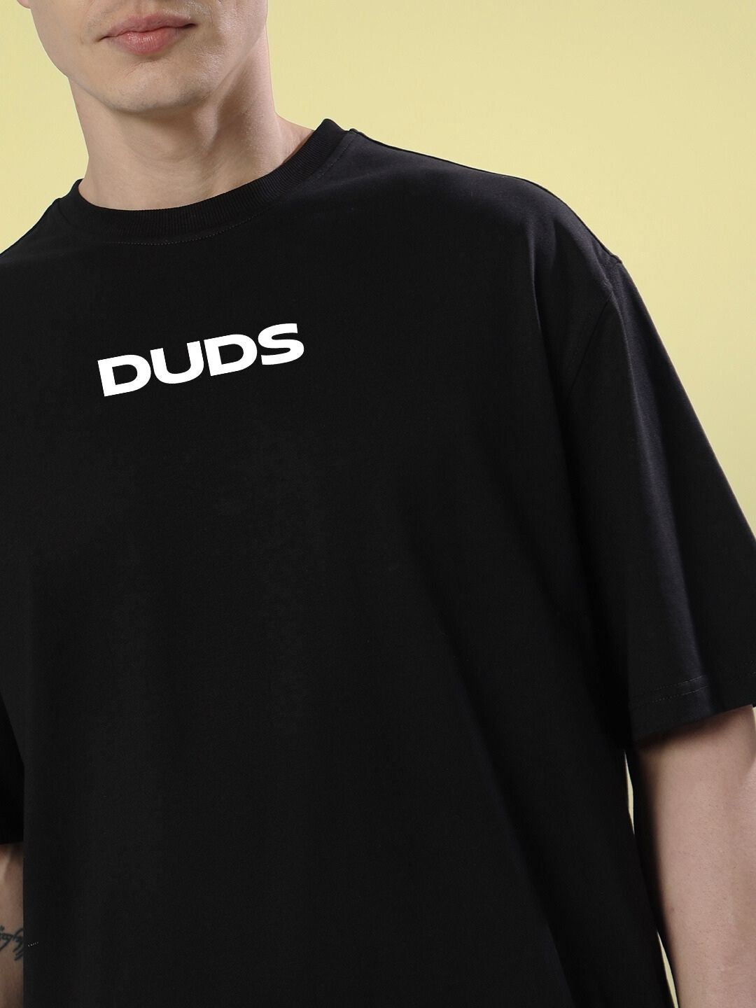 Man wearing a FARARI PRINTED OVERSIZED T-SHIRT BLACK with 'DUDS' printed on the front.