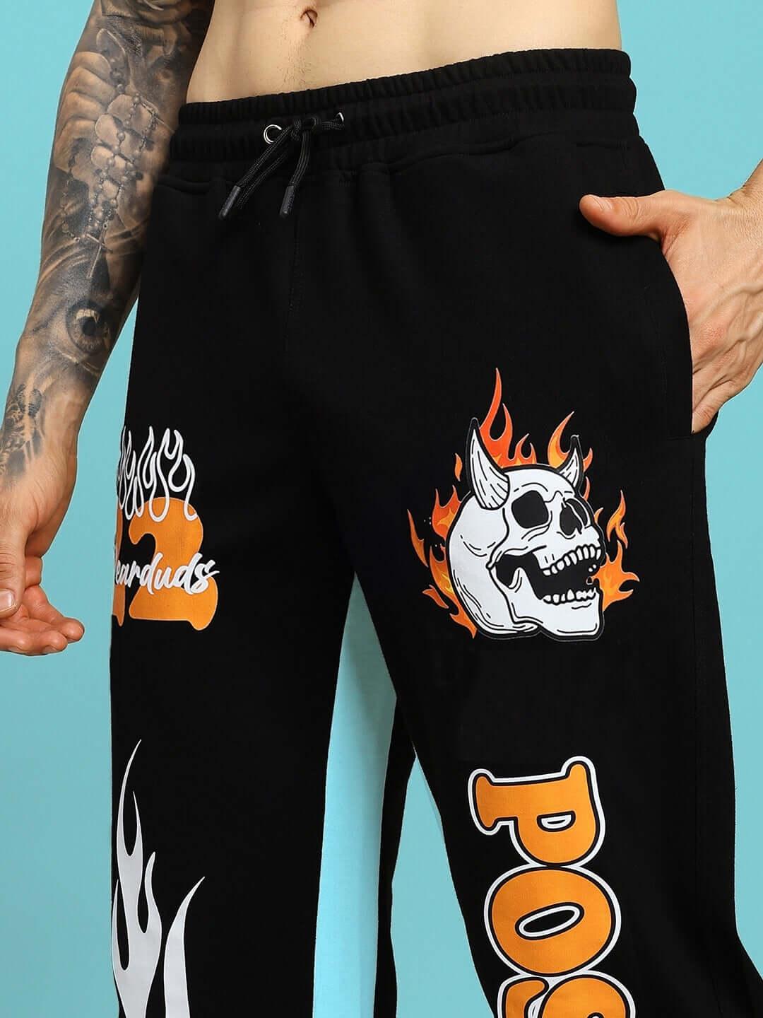 FEARLESS CONTRAST POSITIVE RELAXED FIT JOGGERS BLACK-ORANGE with flame and skull graphics, tattooed arm, lifestyle shot