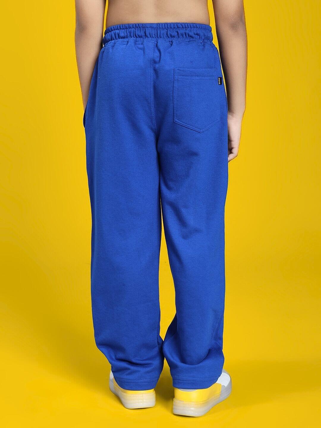 Child wearing FEELING GOOFY JOGGER FOR BOYS AND GIRLS BLUE, showcasing the back view of blue jogger pants on a bright yellow background.