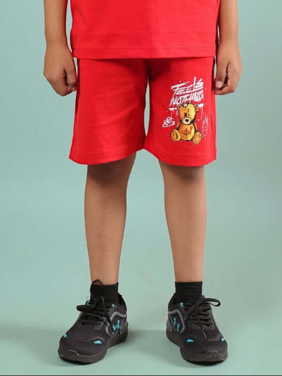 Boy wearing FEELS NOTHING SHORTS FOR BOYS & GIRLS RED with teddy bear graphic.