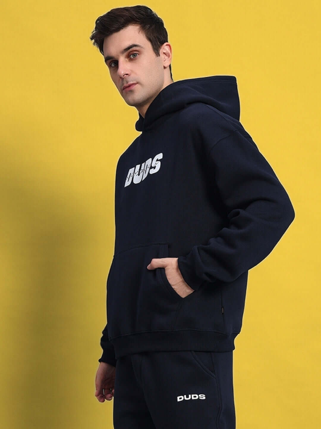 Man wearing navy blue Fight Night fleece hoodie with logo, standing against yellow background