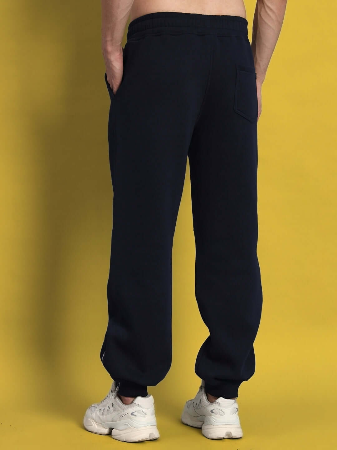 Back view of navy blue Fight Night fleece jogger pants on model, showcasing comfort and fit, paired with white sneakers.