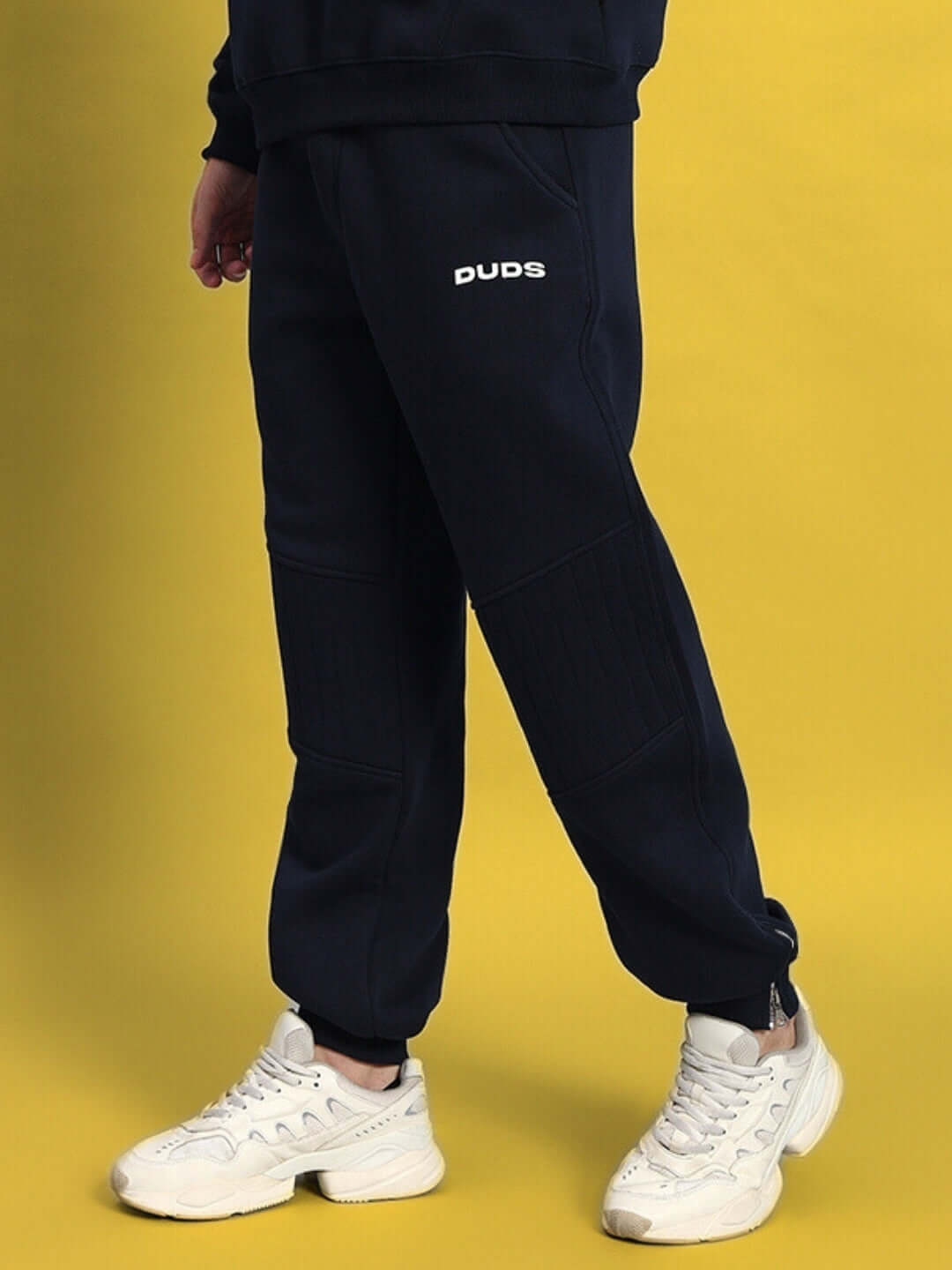 Navy blue fleece joggers with 'DUDS' logo, perfect for fight night, featuring a comfortable fit and stylish design against a yellow background.