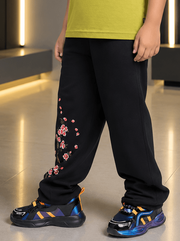 BEAR ON BOARD JOGGER FOR BOYS GIRLS BLACK shown on a child, featuring floral design and paired with trendy sneakers.