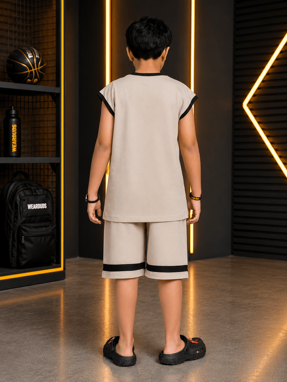 MONO EDGE SLEEVELESS CO-ORD FOR BOYS GIRLS BEIGE worn by a boy from the back in a modern setting.