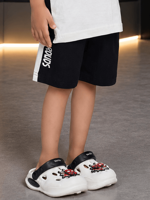 KOALA VIBES SHORTS FOR BOYS GIRLS BLACK worn with playful crocs, showcasing kids' casual style.