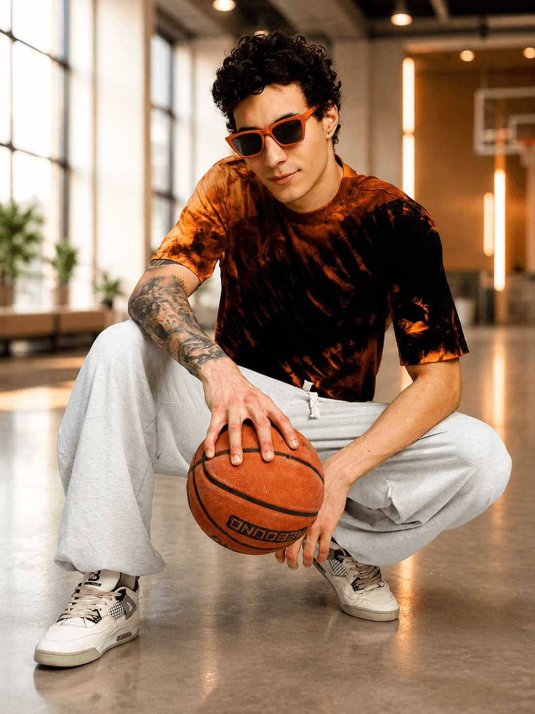 A model posing in a SOLAR TIE-DYE T-SHIRT BLACK FIRE ORANGE while holding a basketball.