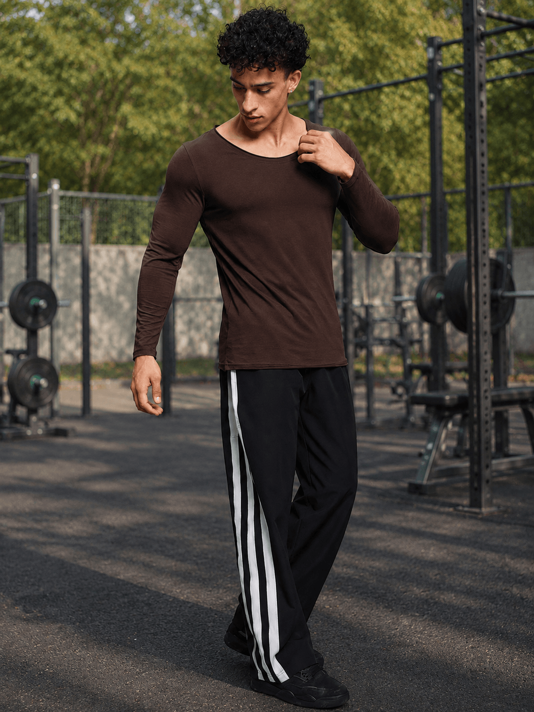 Model wearing JOEL SLIM FIT COTTON SWEATSHIRT BROWN with black and white stripe pants in an outdoor gym.