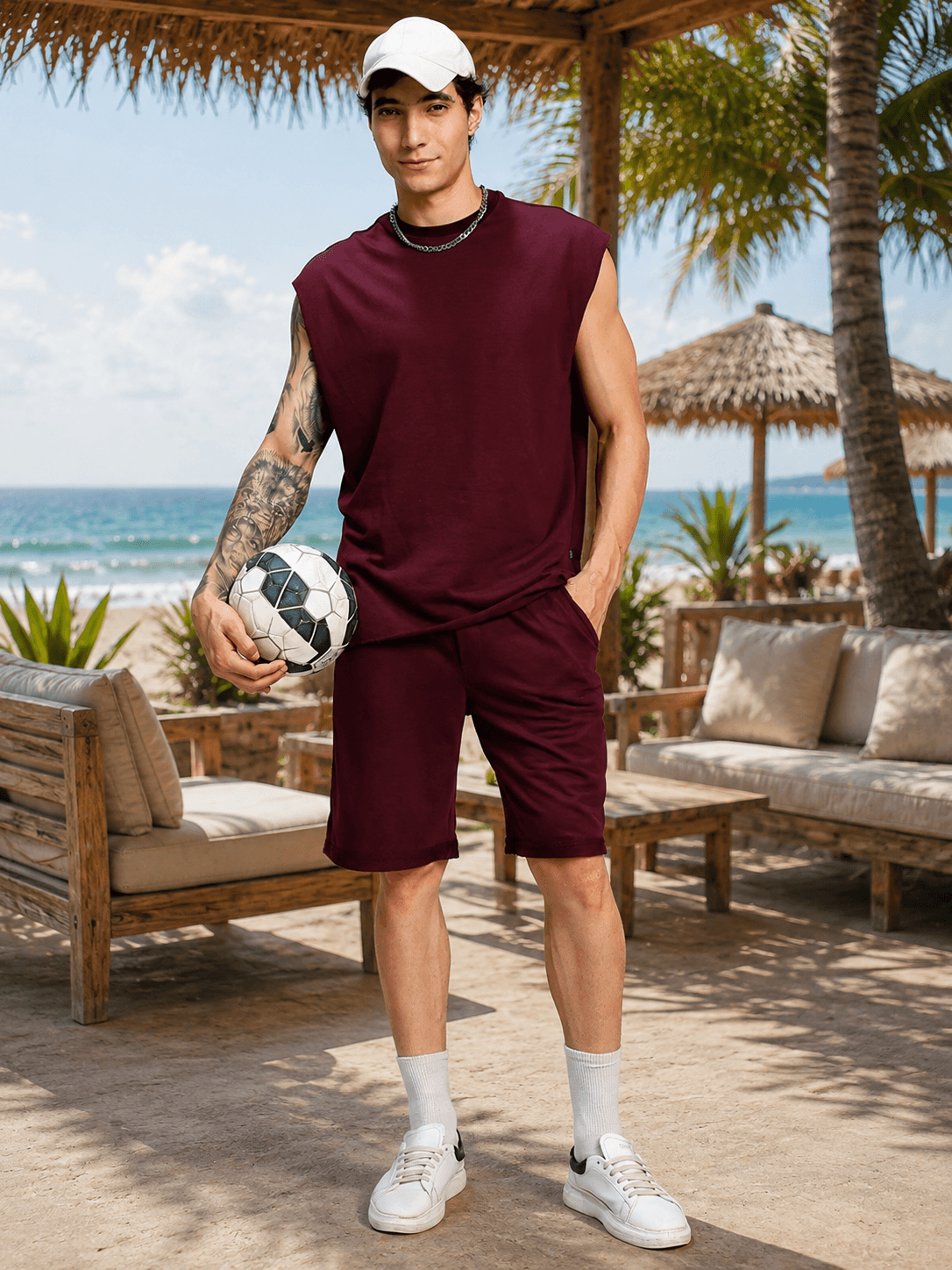 DRIVE MONOCHROME CO-ORD SET MAROON model holding a soccer ball, standing on the beach in sunny weather.