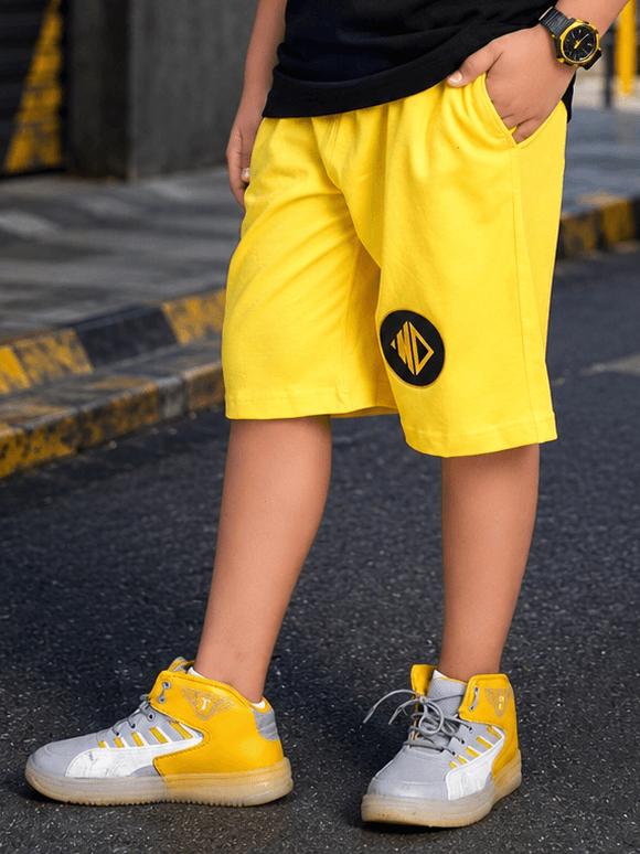 MIDNIGHT BAT SHORTS FOR BOYS GIRLS YELLOW worn by a child, featuring a vibrant yellow color and unique logo design.
