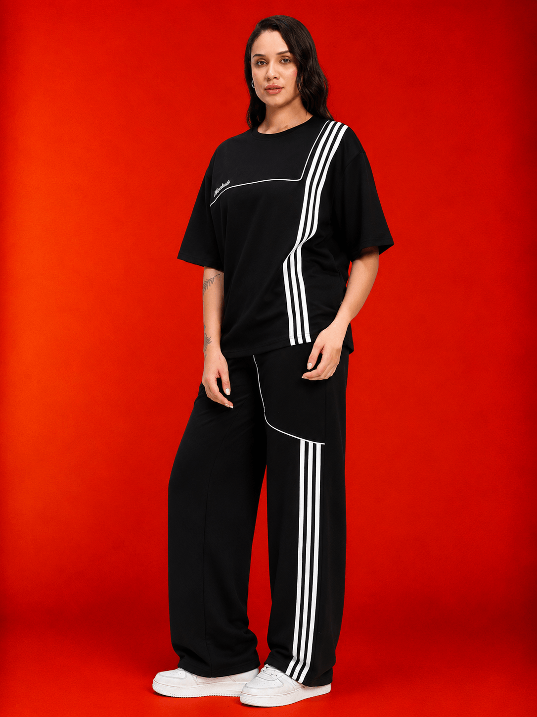 Women Youth Contrest Piping Joggers Black worn by model against a bold red background, showcasing modern sporty style.
