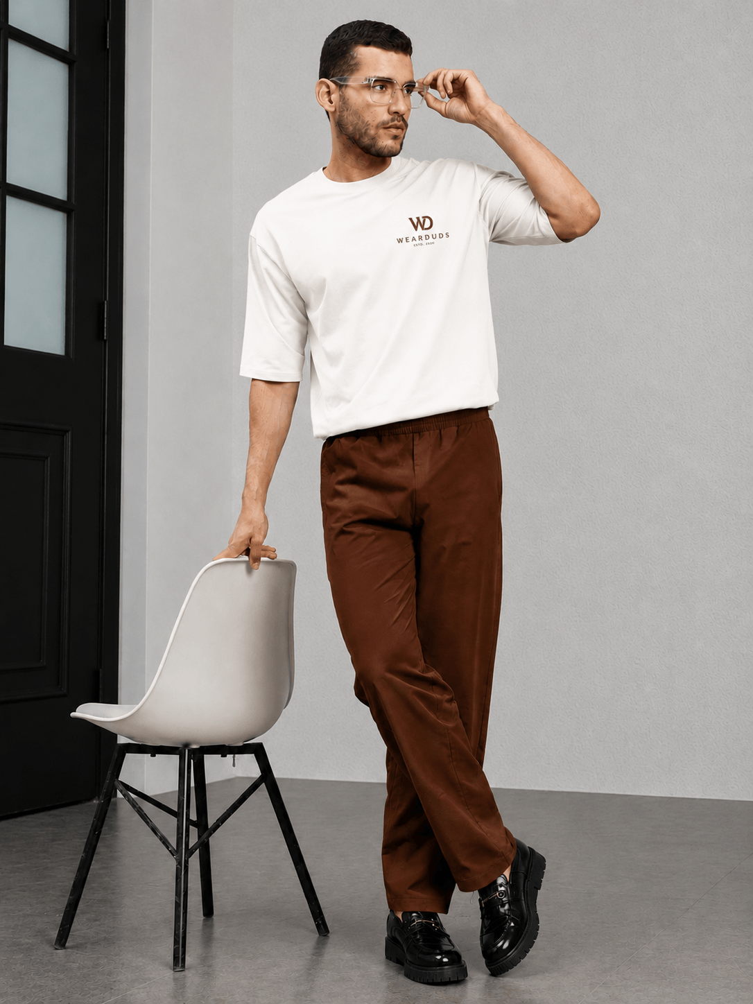 ATHLETIC DRESS TRACK TROUSERS BROWN showcased on a man wearing a white shirt and stylish glasses.