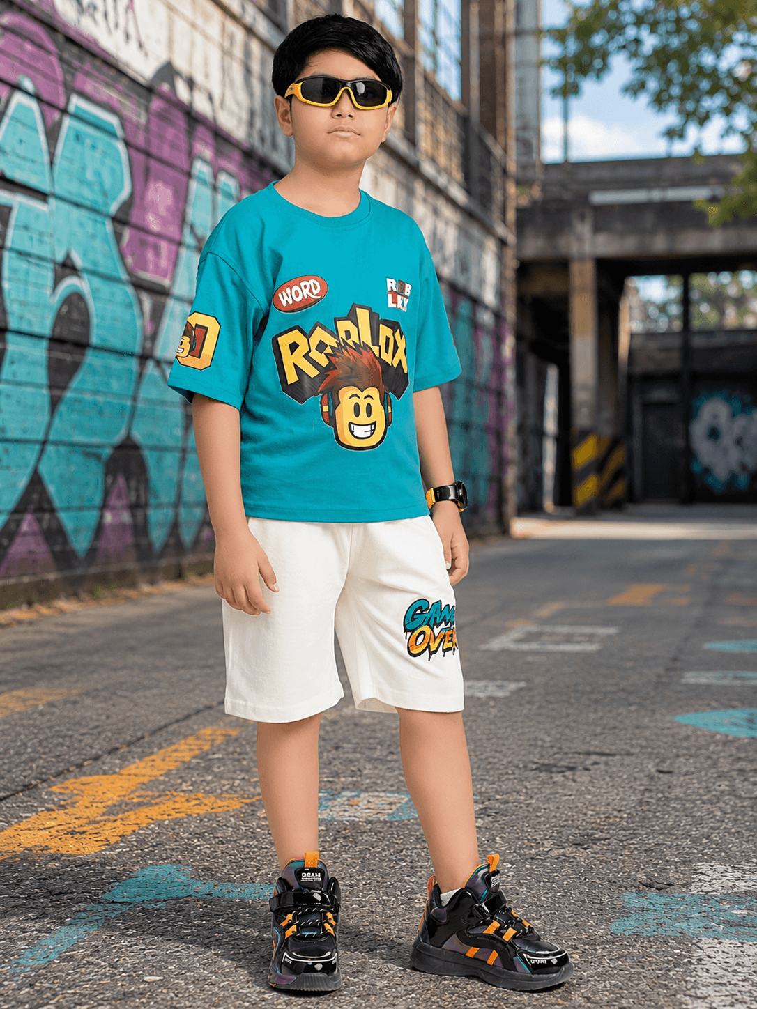 JUNIOR SHORTS FOR BOYS GIRLS WHITE worn by a child in a vibrant urban setting with graffiti.
