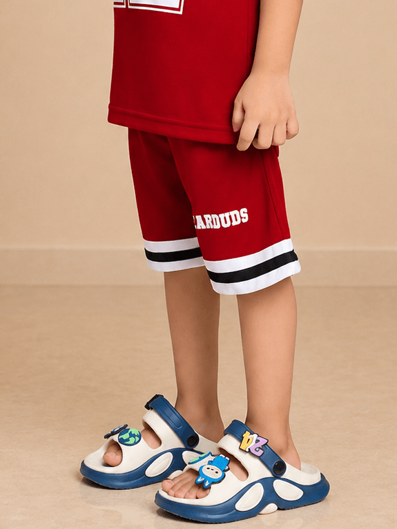 KING 22 VARSITY COOL SHORTS FOR BOYS GIRLS RED worn by a child with colorful sandals, showcasing sporty style.