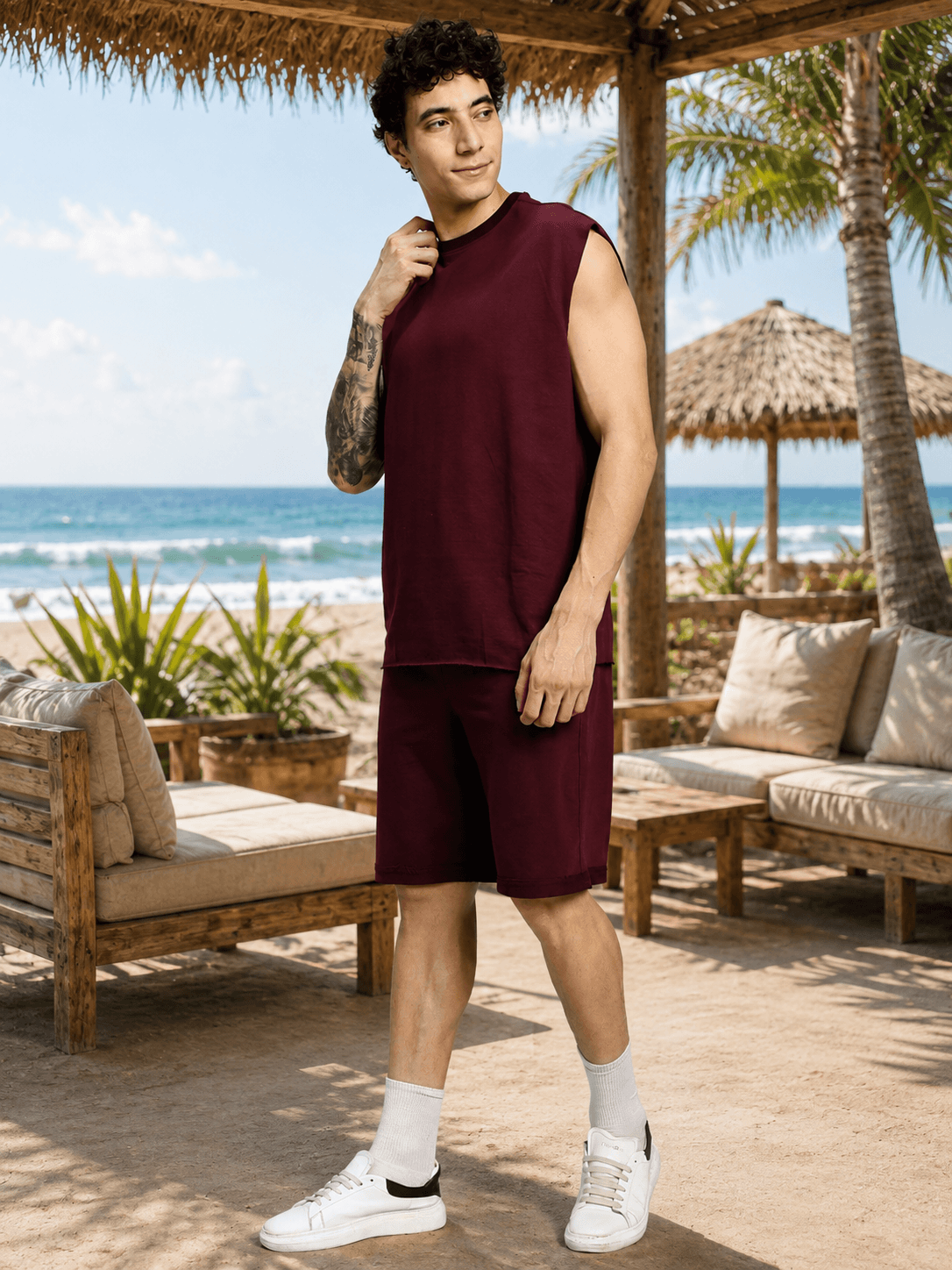 DRIVE MONOCHROME SLEEVELESS T-SHIRT MAROON worn by a man on the beach, showcasing a bold streetwear style.