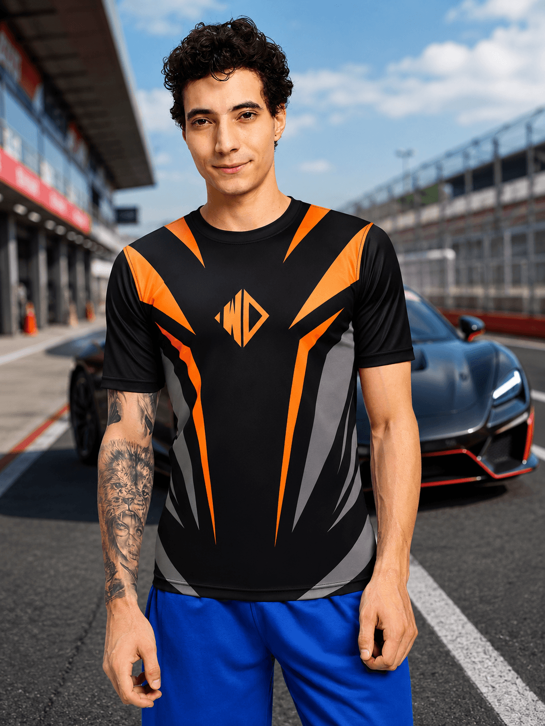 NITRO SHIFT ATHLETIC T-SHIRT BLACK on a model standing near a sports car on a racetrack.
