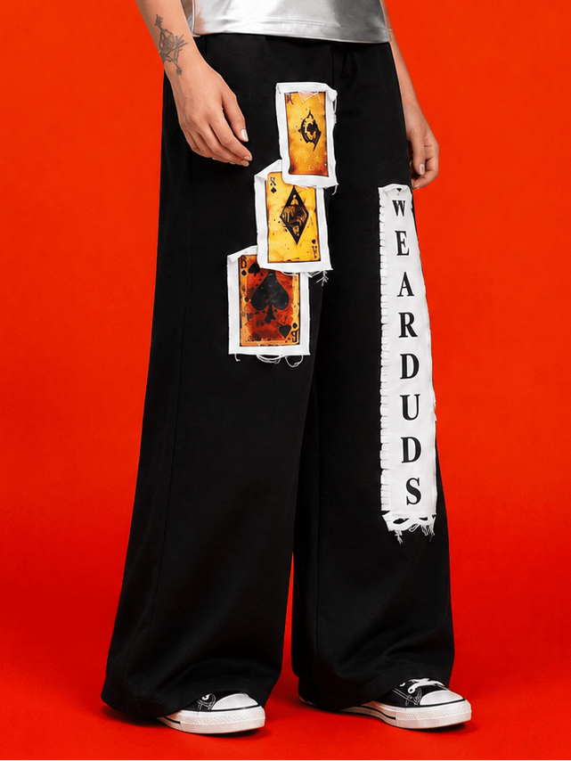 WOMEN WILDCARD RAW-CANVAS GRAPHIC JOGGERS BLACK with bold graphics on a vibrant red background.