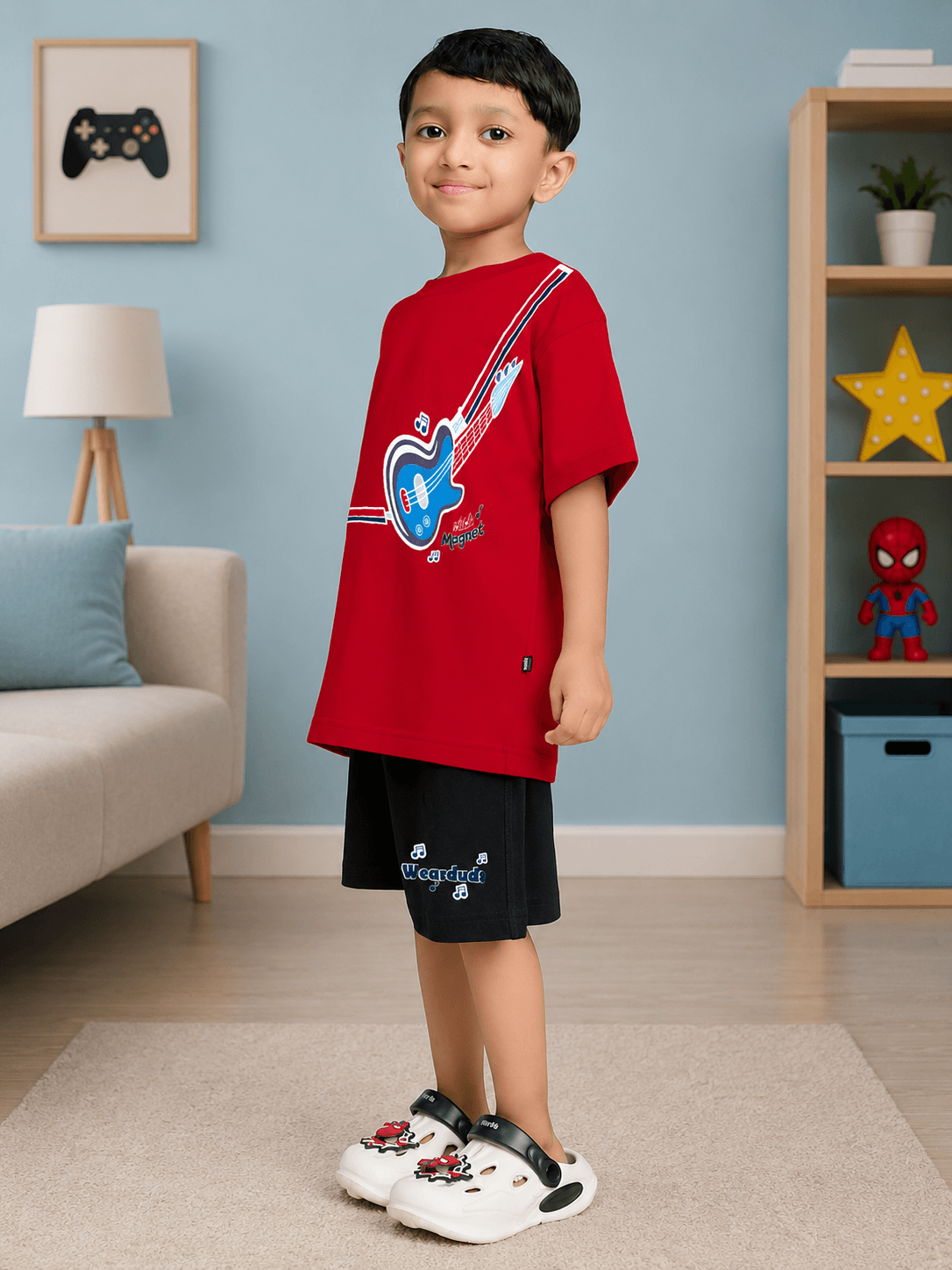 LITTLE ROCKSTAR CO-ORD FOR BOYS & GIRLS RED BLACK worn by a boy, featuring a red shirt with a guitar design and black shorts.