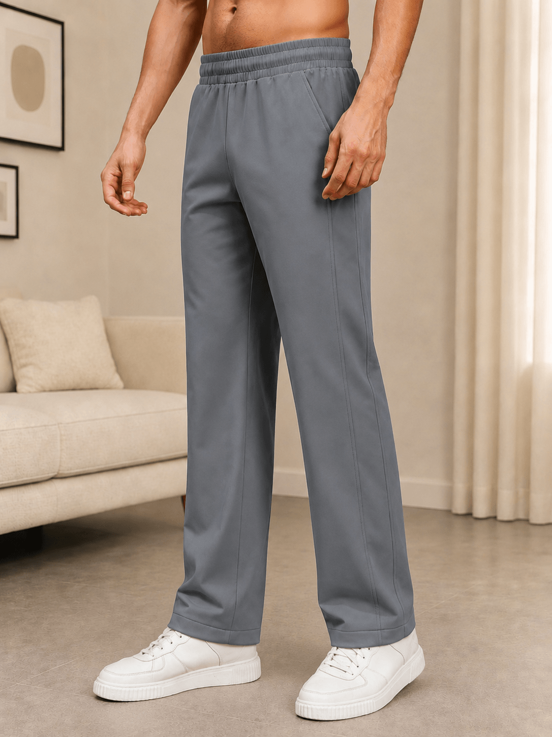 ATHLETIC DRESS TRACK TROUSERS GREY displayed on a model wearing white sneakers in a stylish living room setting.