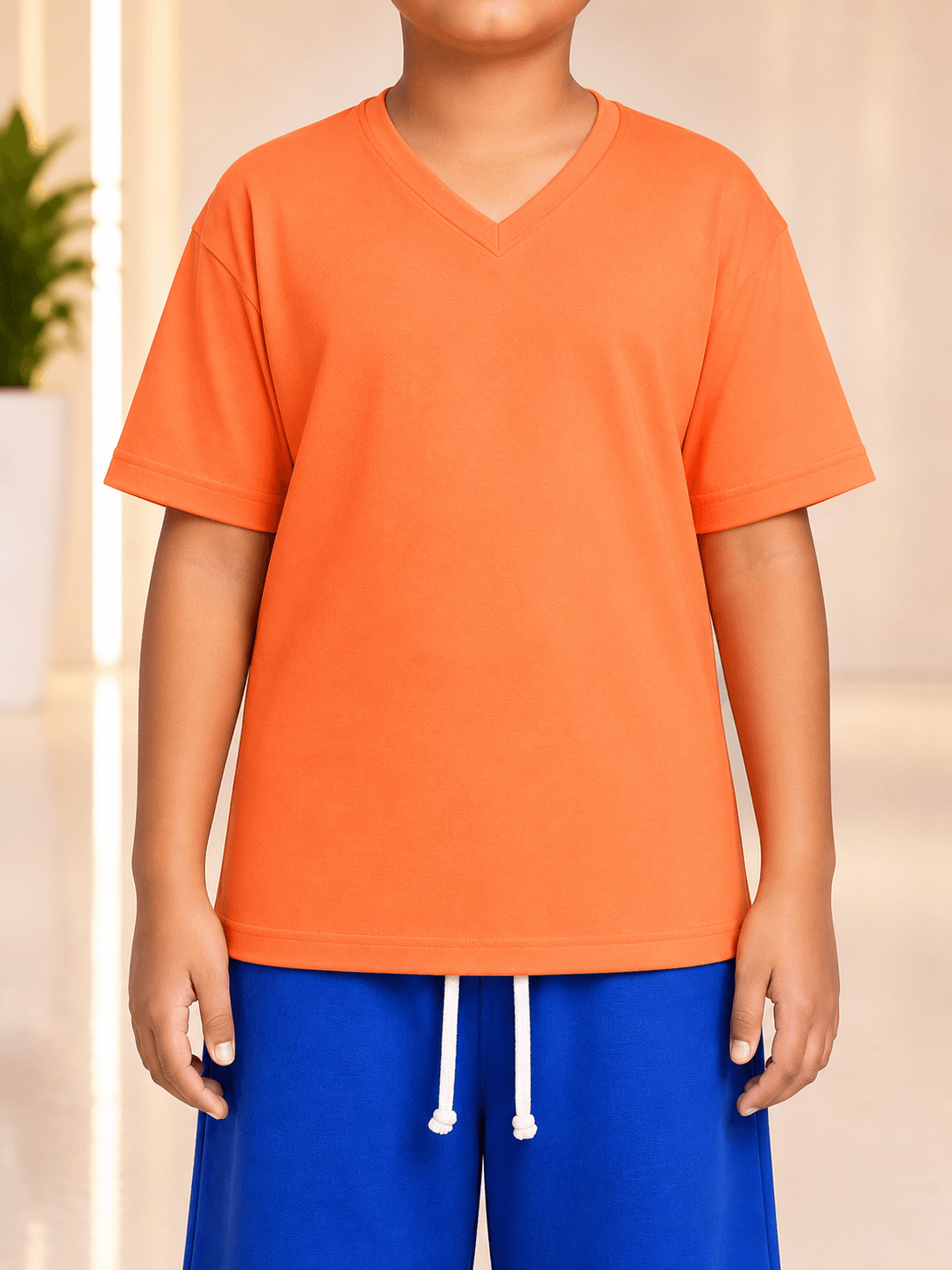COOLFIT CO-ORD FOR BOYS GIRLS ORANGE BLUE - Boy wearing vibrant orange v-neck shirt and blue shorts.