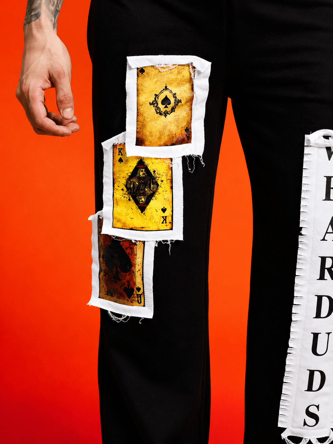 Close-up of WILDCARD RAW-CANVAS GRAPHIC JOGGERS BLACK featuring bold graphic patches on black fabric.