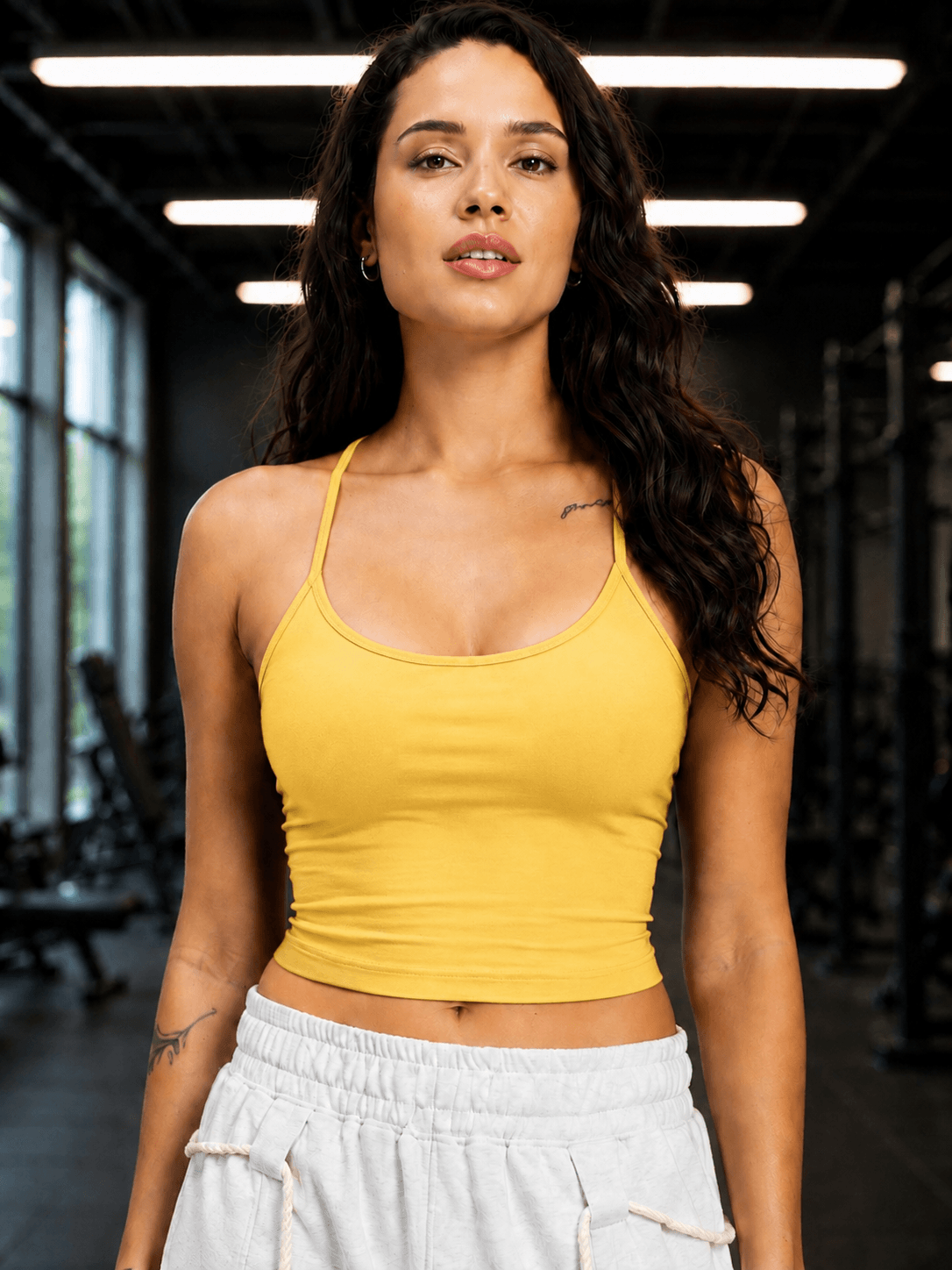 WOMEN SEAMLESS COTTON CROP-TOP YELLOW worn by a woman in a gym setting, showcasing a stylish and modern look.