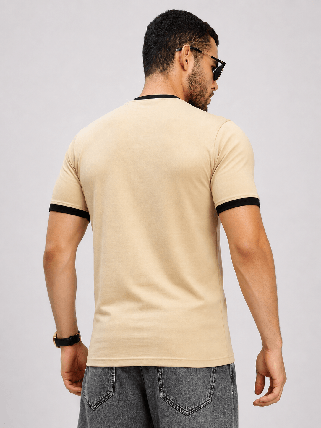 Back view of a man wearing the MINIMALIST CONTRAST EDGE T-SHIRT BEIGE with black contrast edges.