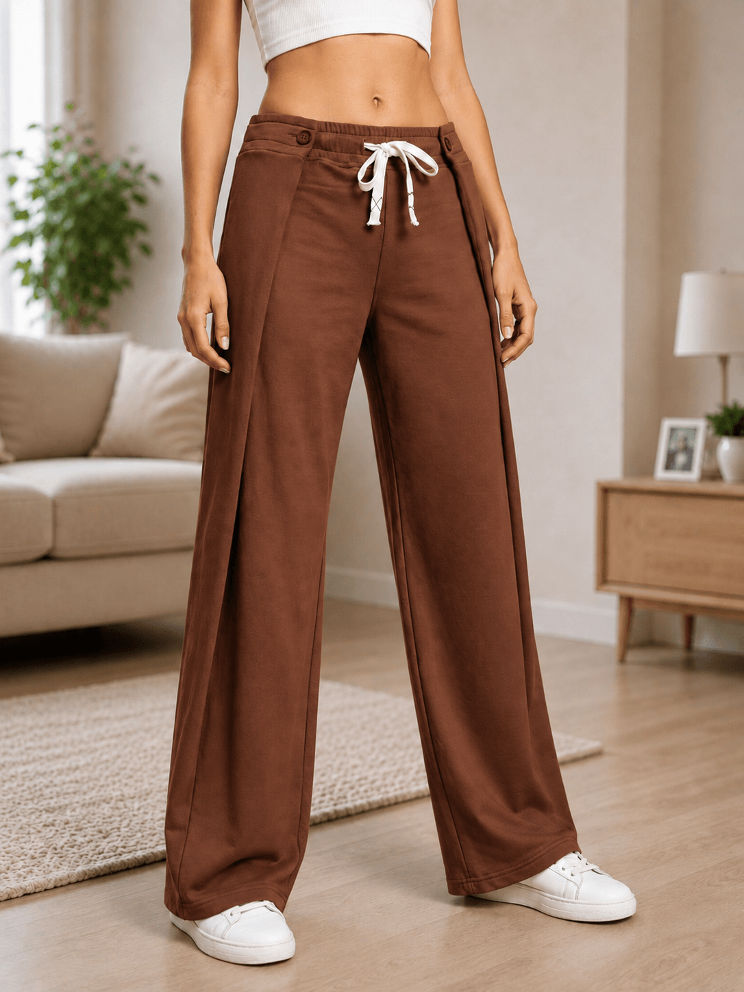 WOMEN OMEGA FLOW WIDE FIT JOGGERS DARK BROWN worn by a model in a stylish living room setting.