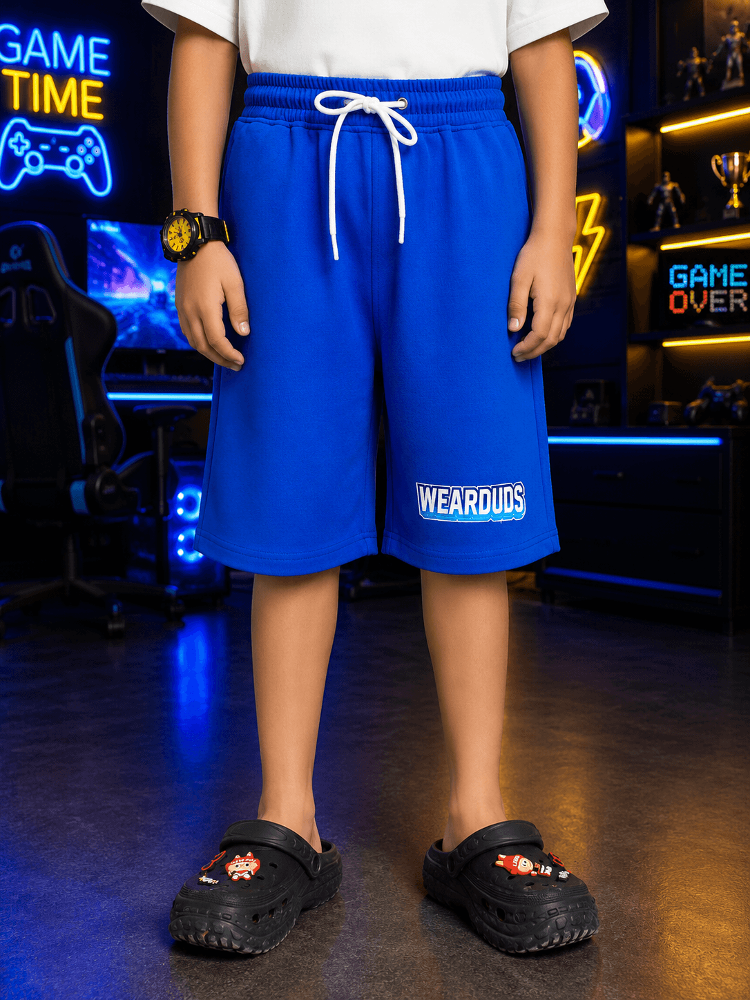 FUSION SHORTS FOR BOYS GIRLS BLUE worn by a child, featuring elastic waistband and gaming-themed backdrop.