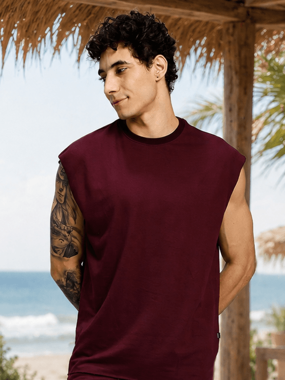 DRIVE MONOCHROME SLEEVELESS T-SHIRT MAROON worn by a man at the beach against a tropical backdrop.