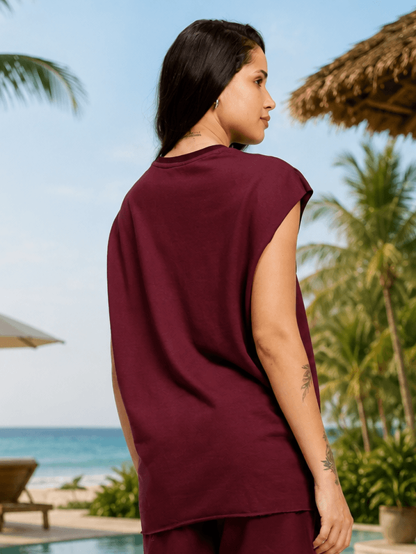 Women Drive Monochrome Sleeveless T-Shirt Maroon showcased in a relaxed beach setting with palm trees.