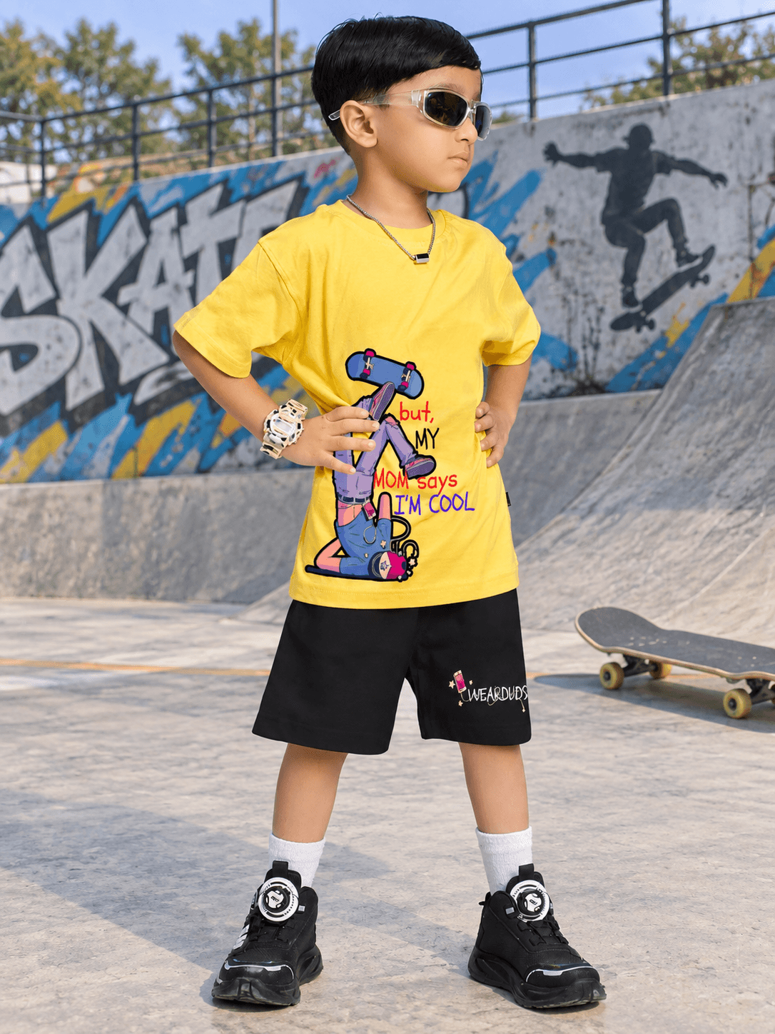 COOL DUDE SKATER SHORTS FOR BOYS GIRLS BLACK worn by a child in a skater park, showcasing a trendy and casual style.