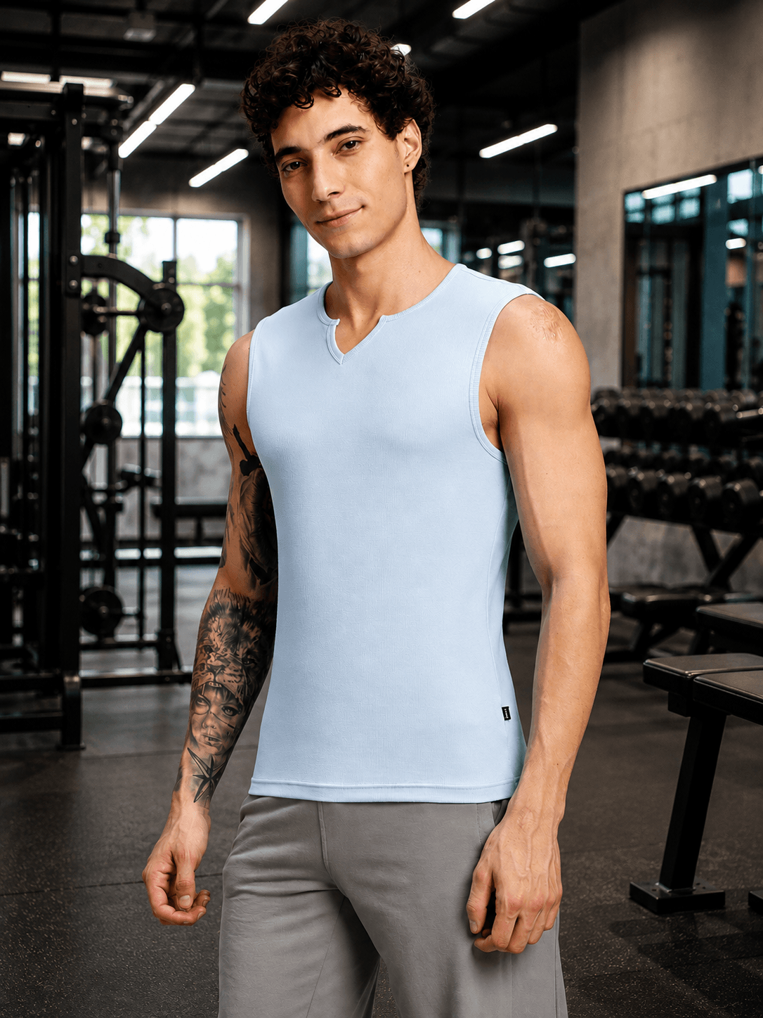 MUSCLE FIT SLEEVELESS GYM T-SHIRT SKY BLUE worn by a fit man in a gym setting, showcasing modern fitness style.
