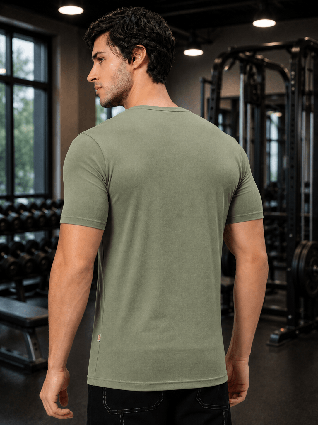 Man wearing BEDROCK FIT REGULAR FIT T-SHIRT ROYAL SAGE GREEN in a gym setting.
