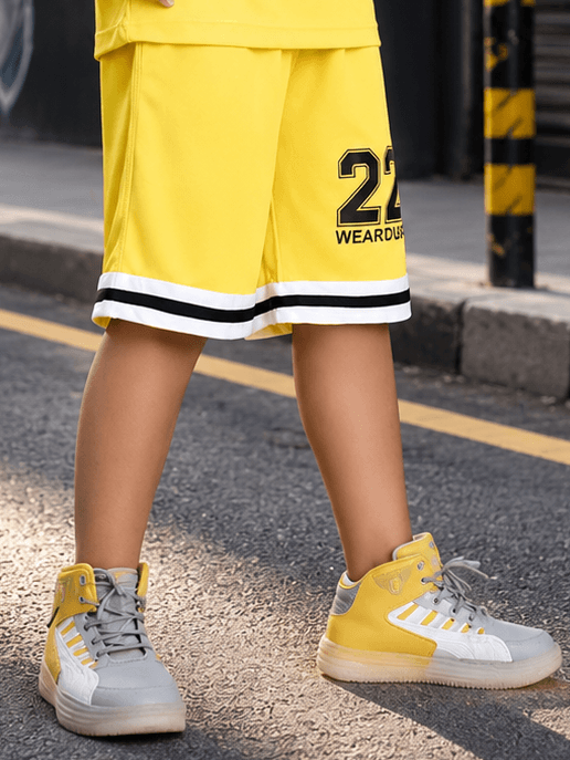 THE STREET SHORTS FOR BOYS GIRLS YELLOW worn by a child on a city street, featuring vibrant yellow color and sporty style.