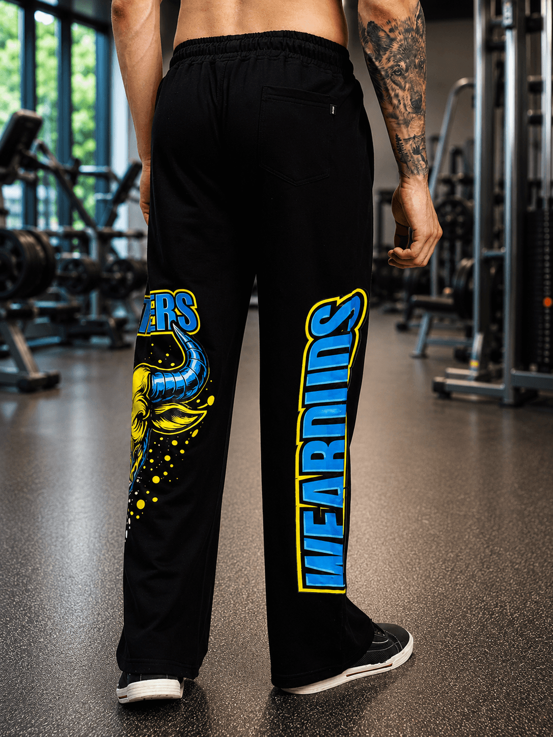 BULL RELAXED-FIT WIDE LEG JOGGER BLACK featuring bold graphics and a wide-leg silhouette in a gym setting.