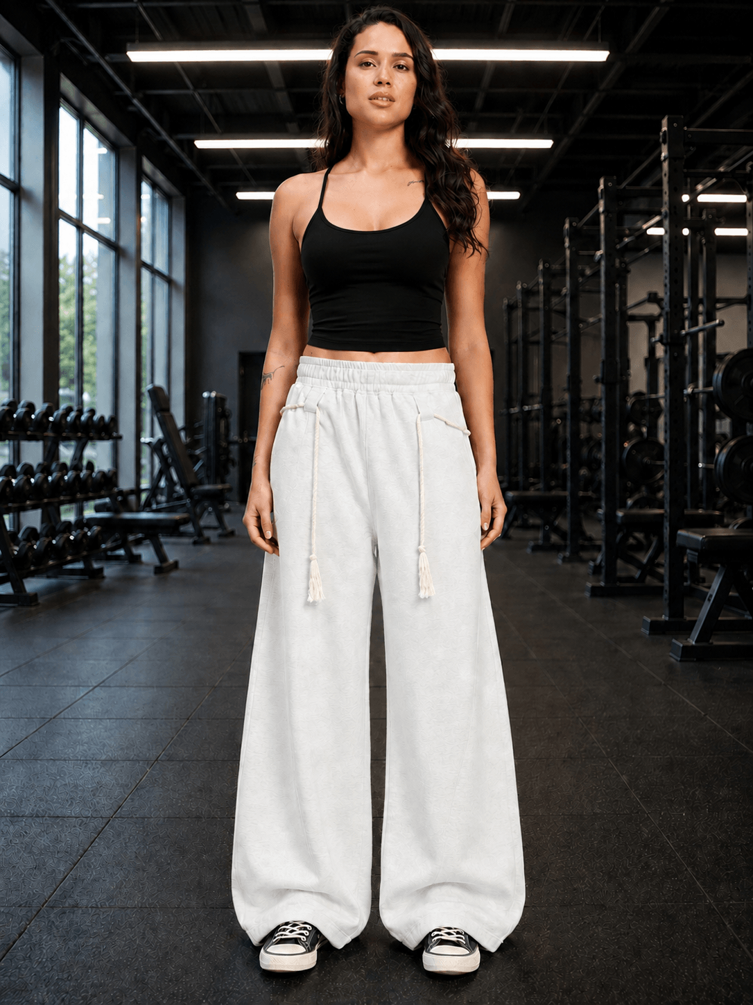 WOMEN SEAMLESS COTTON CROP-TOP BLACK worn with loose white pants in a gym setting, showcasing modern fitness style.