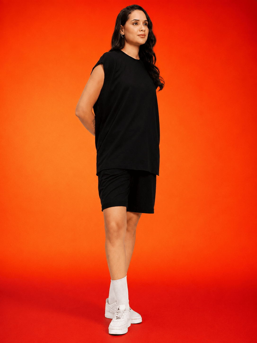 Women Drive Monochrome Sleeveless T-Shirt Black worn by a model against an orange background, showcasing sporty-chic style.