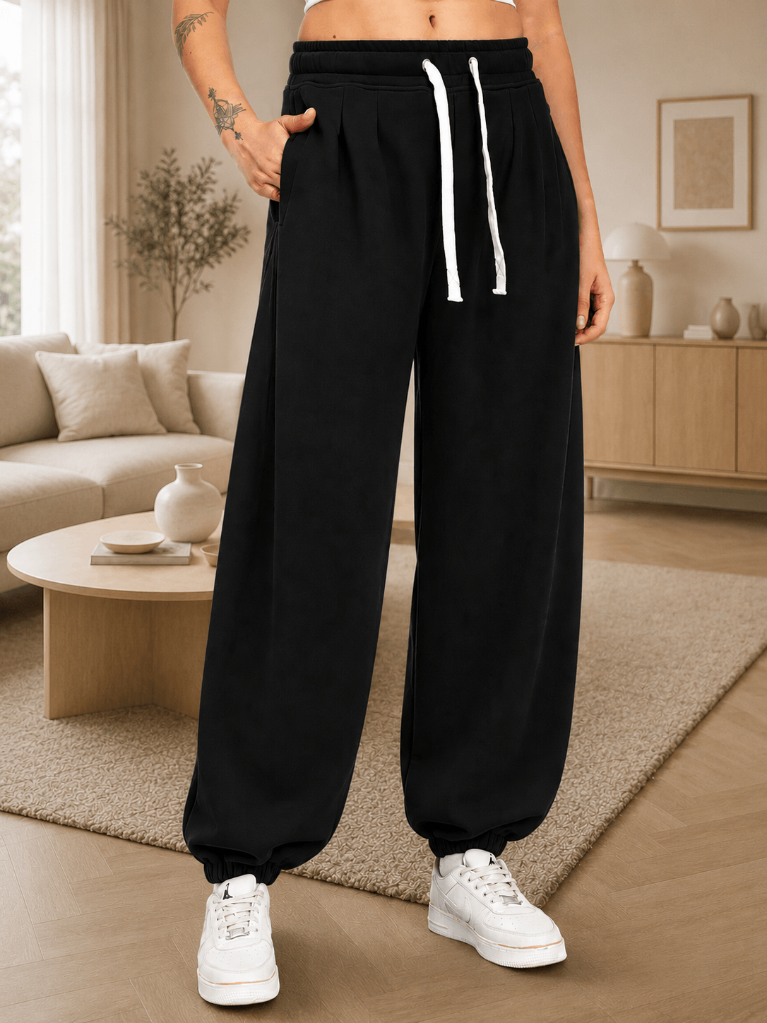 WOMEN COOLFIT BAGGY LOOSE FIT JOGGER BLACK showcased on a model in a modern living room setting.