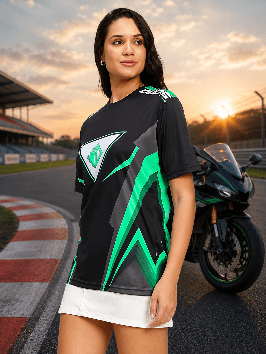 Women Apex Racing Regular T-Shirt Black worn by a model at a racetrack with a motorcycle in the background.