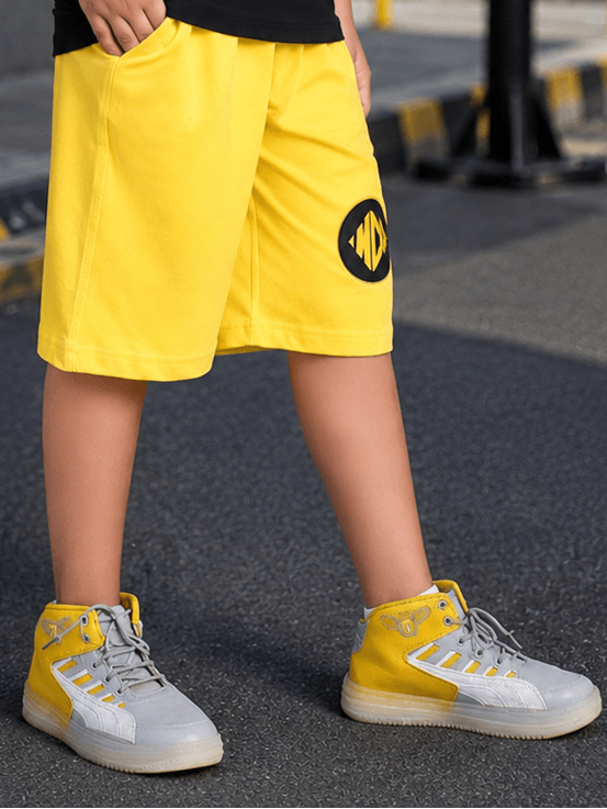 MIDNIGHT BAT SHORTS FOR BOYS GIRLS YELLOW worn by a child on the street, showcasing vibrant style and comfort.