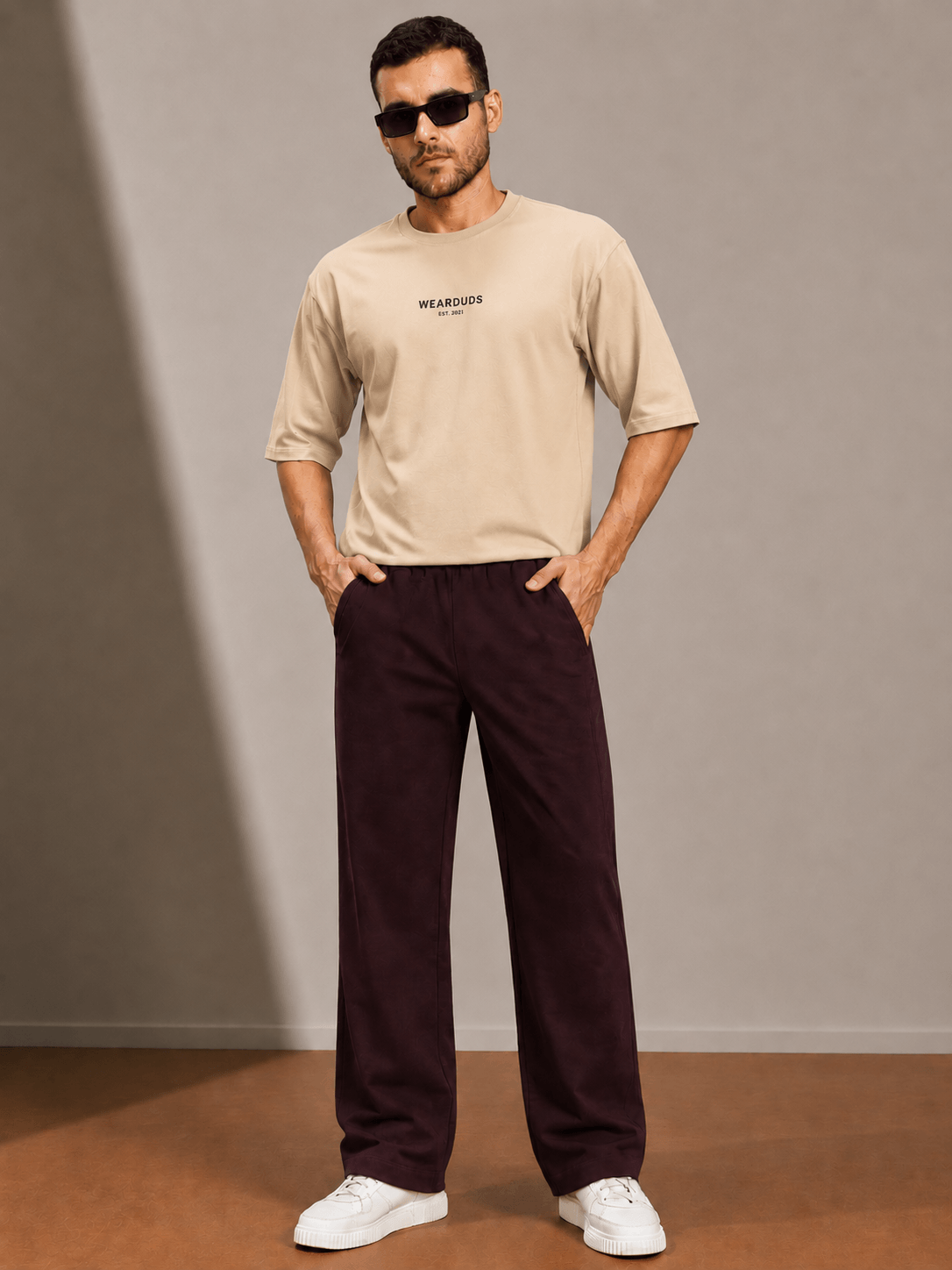 Man wearing ATHLETIC DRESS TRACK TROUSERS MAROON with a beige shirt and sunglasses, showcasing a stylish sporty look.