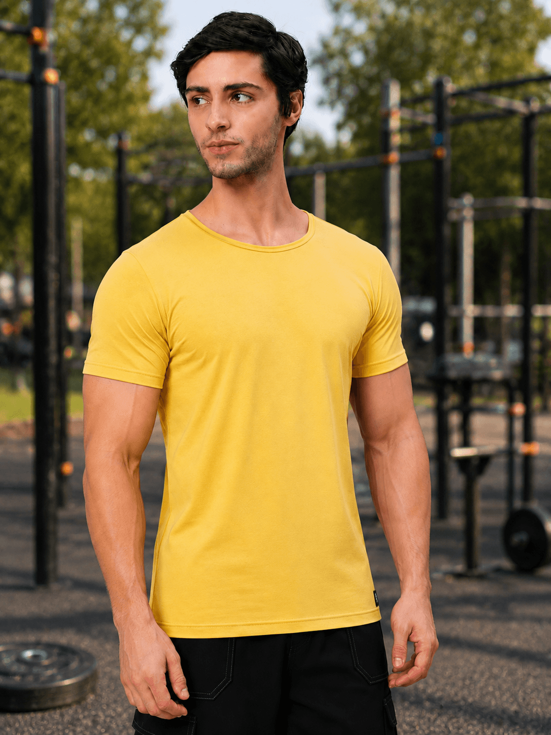 Man wearing BEDROCK FIT REGULAR FIT T-SHIRT YELLOW in an outdoor gym setting.