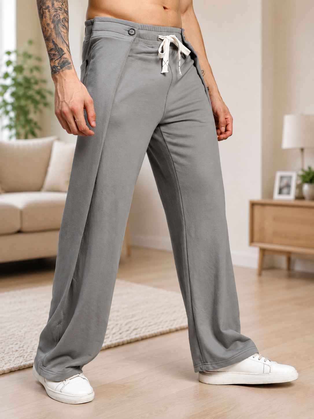 OMEGA FLOW WIDE FIT JOGGERS GREY stylishly displayed on a model in a modern living space.