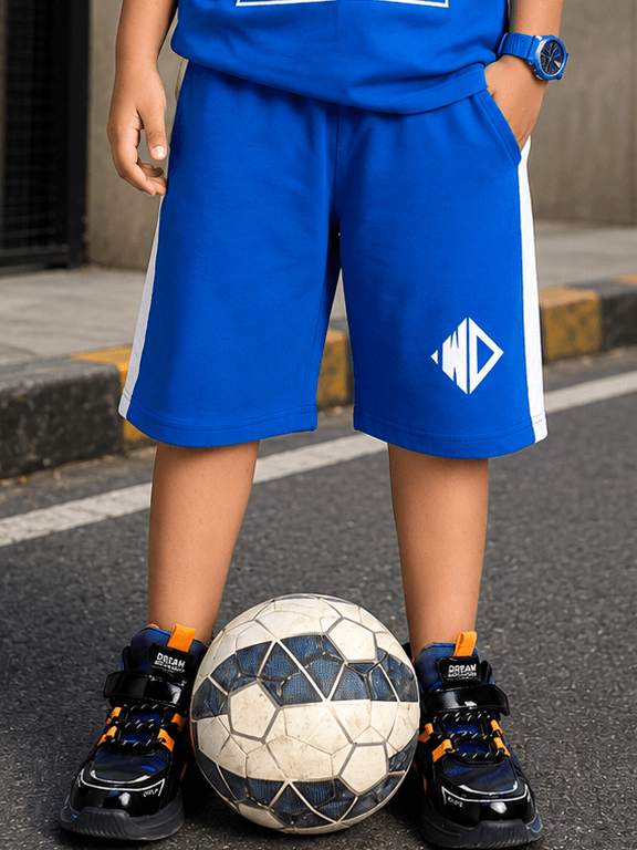 Electric Flex Shorts for Boys Girls Blue worn by a child standing with a soccer ball on the street.