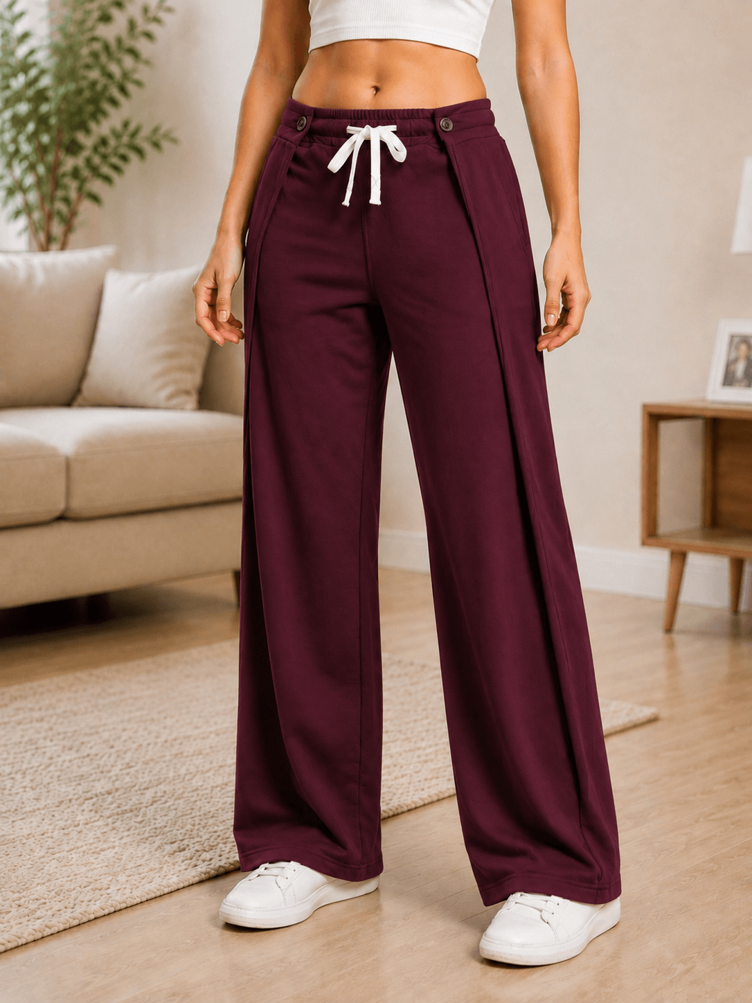 WOMEN OMEGA FLOW WIDE FIT JOGGERS MAROON displayed in a stylish living room setting, showcasing their relaxed silhouette.